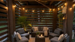A covered outdoor seating area with wicker furniture, string lights, and a potted plant. - Angler’s Hideaway: Your Peaceful Escape for Fishing, Fun & Relaxation (Homosassa)