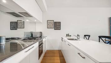 A modern kitchen with a central island, stainless steel appliances, and framed botanical prints on the wall.