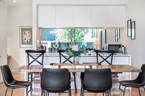 A modern kitchen with a central island, black chairs, and a large window.