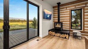 Ein modernes Interieur mit Kamin, großem Fenster und Blick auf eine grüne Landschaft.