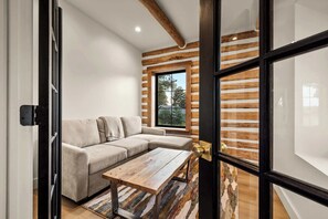 A modern interior with a wooden slat wall, a beige sectional sofa, and a wooden coffee table. - The Willow House - Hot Tub w/ Views near Glacier (Columbia Falls)