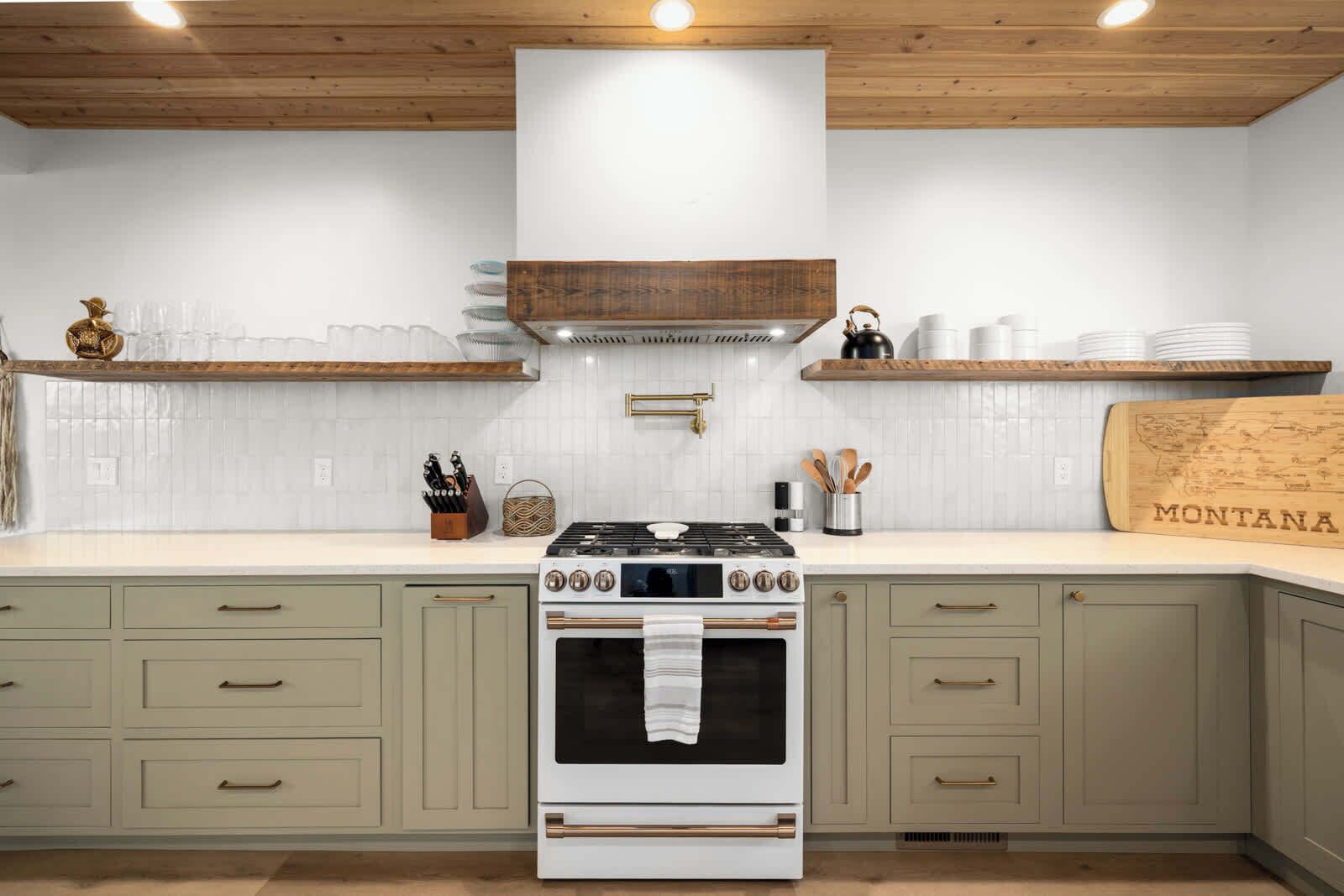 A kitchen with a stove, oven, and wooden shelves.