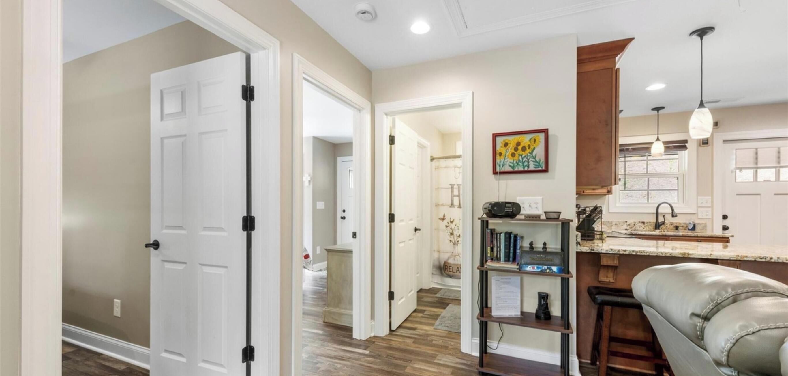 A hallway leading to a kitchen with a bar area, a bookshelf, and a couch.