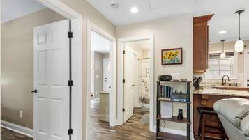 A hallway leading to a kitchen with a bar area, a bookshelf, and a couch.