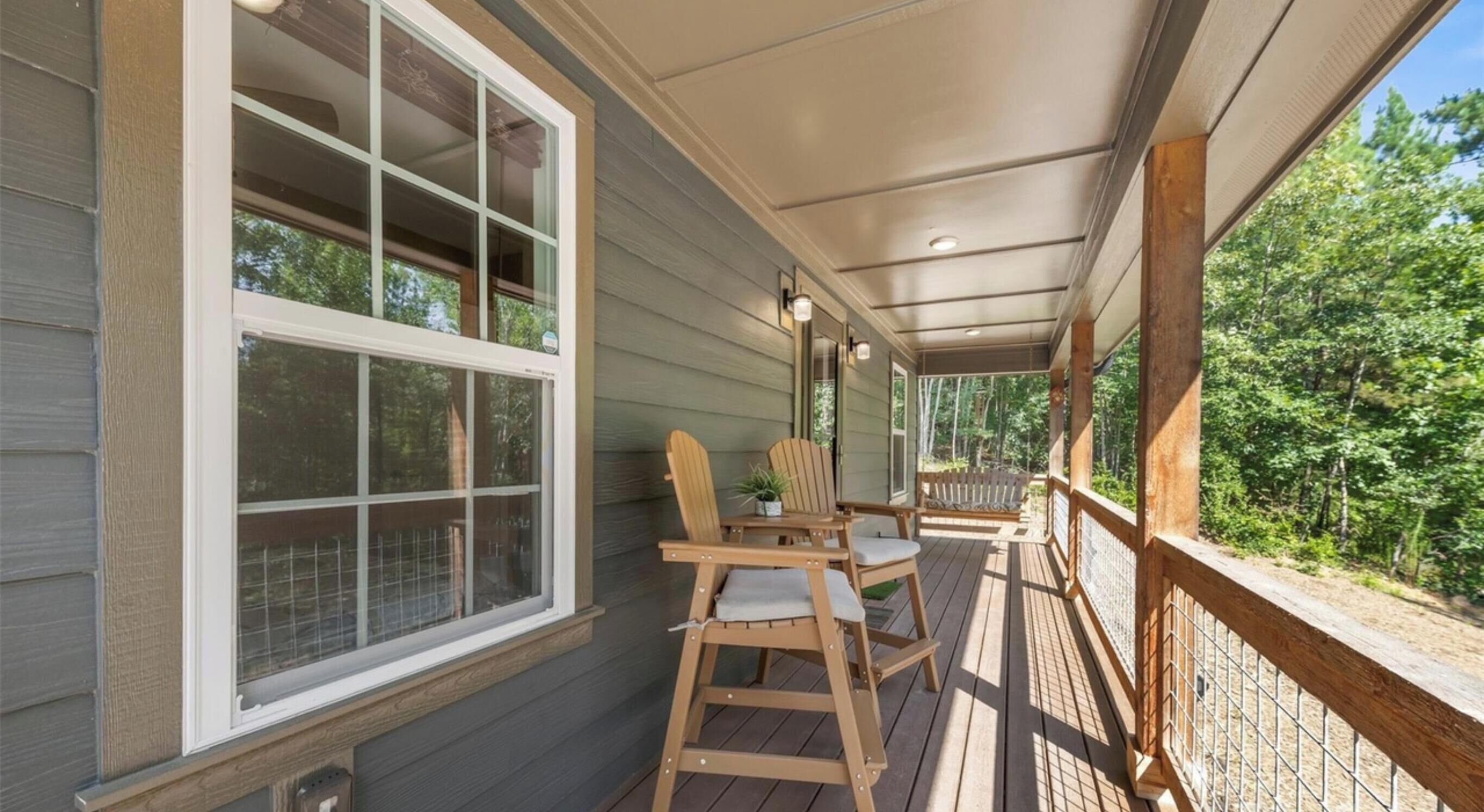 A covered porch with wooden furniture, a table, and chairs.