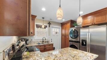A kitchen with granite countertops, stainless steel appliances, wooden cabinets, and pendant lighting.