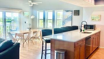 A modern kitchen with a central island, wooden cabinets, and a stainless steel trash can.