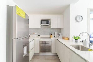 A compact kitchen with a built-in oven, microwave, and stainless steel refrigerator. - The best choice in San José—spotless and comfortable (Merced)