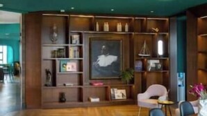 Uma sala de conferências com uma mesa de madeira, cadeiras e uma estante com diversos objetos.