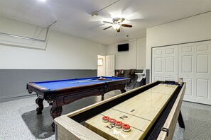 Ett rum med ett biljardbord, ett shuffleboard-bord och en takfläkt.