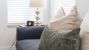 A room with a blue sofa, a lamp, and a clock on a bedside table. - 639 - Stylish and newly renovated 6 Bedroom Home 5 Star (Davenport)