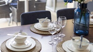 Een eettafel gedekt met borden, kommen en wijnglazen, met een bloemenvaas op tafel.