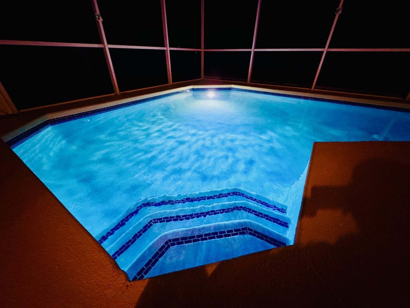A swimming pool with a tiled edge and a dark surrounding wall.