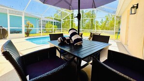 Een terras buiten met een zwembad, een tafel en stoelen.