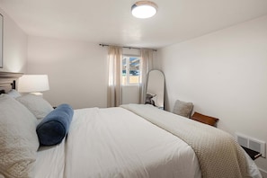 Ein Hotelzimmer mit Bett, Spiegel, Fenster mit Vorhängen und Heizkörper.
