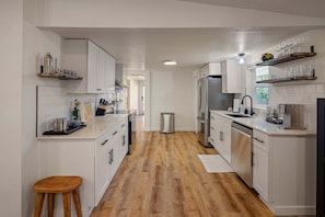 Eine Küche mit weißen Schränken, Holzboden und einem Edelstahl-Kühlschrank.