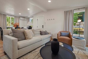 Ein modernes Wohnzimmer mit einer Couch, Sesseln, einem Couchtisch und einer Lampe.
