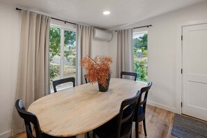 A dining area with a round table, four chairs, and a potted plant.