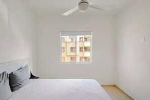 A bedroom with a bed, a ceiling fan, a window, and a view of a building outside. - Your peaceful retreat in Playa del Carmen (Playa del Carmen)