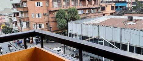 A balcony with a view of a multi-story building with balconies and air conditioning units.