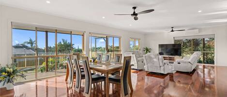 A spacious living area with a dining table, chairs, a sofa, and a TV.