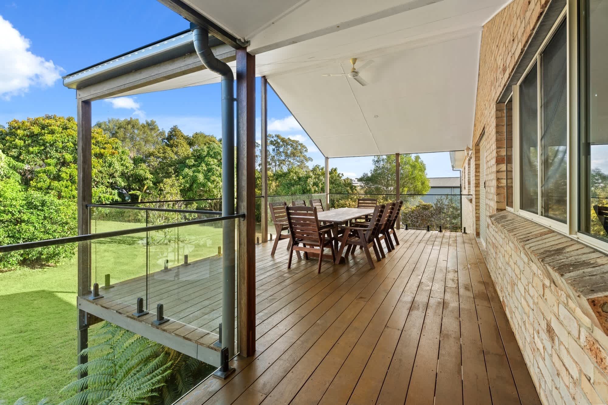 A covered outdoor patio with a table and chairs, overlooking a lush garden.