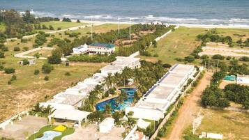 An aerial view of a resort with multiple buildings, a swimming pool, and a view of the ocean.