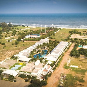 Oversigtsbillede af et resort med flere bygninger, en swimmingpool og udsigt til havet.