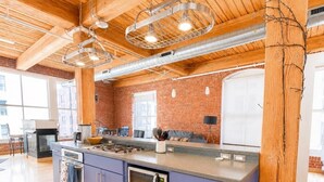 Une cuisine moderne dotée d’un îlot central, d’appareils électroménagers en acier inoxydable et d’un plafond en bois.