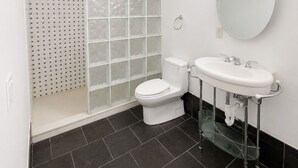 A modern bathroom with a toilet, sink, and shower.