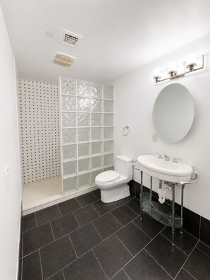 A modern bathroom with a toilet, sink, and shower.