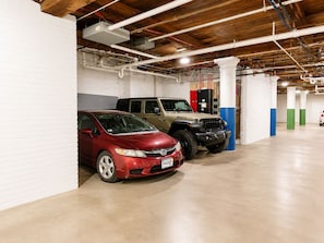 A parking garage with two cars parked, wooden beams on the ceiling, and white pillars. - Elevated Downtown Extended Stay in a Nearly 2,000-Square-Foot Loft (St. Louis)