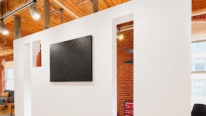 Un intérieur moderne avec un plafond en bois, une cloison blanche ornée d’une œuvre d’art noire, et une boîte à outils rouge en arrière-plan.