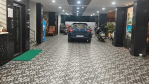 Una hall d'albergo con pavimento a motivi, un'auto parcheggiata al centro e una motocicletta alla destra.