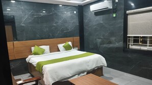 Una camera d'albergo moderna con una parete in marmo, una struttura letto in legno, una coperta bianca e una coperta verde.