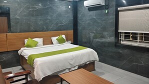 Una moderna camera d'albergo con una parete in marmo, un letto con copripiumino verde e bianco, una testiera in legno, un comodino e un condizionatore.