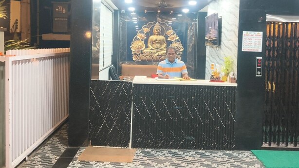 Un'area reception hotel con una receptionist, una statua di Buddha e una segnaletica che indica il nome dell'hotel e i piani.