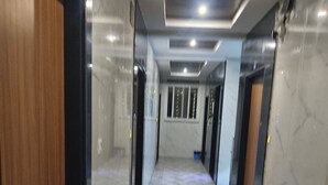 Un corridoio con pavimento a motivi a spina di pesce, porte su entrambi i lati e soffitto con illuminazione a incasso.