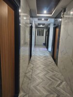 A hallway with a herringbone patterned floor, doors on both sides, and a ceiling with recessed lighting.