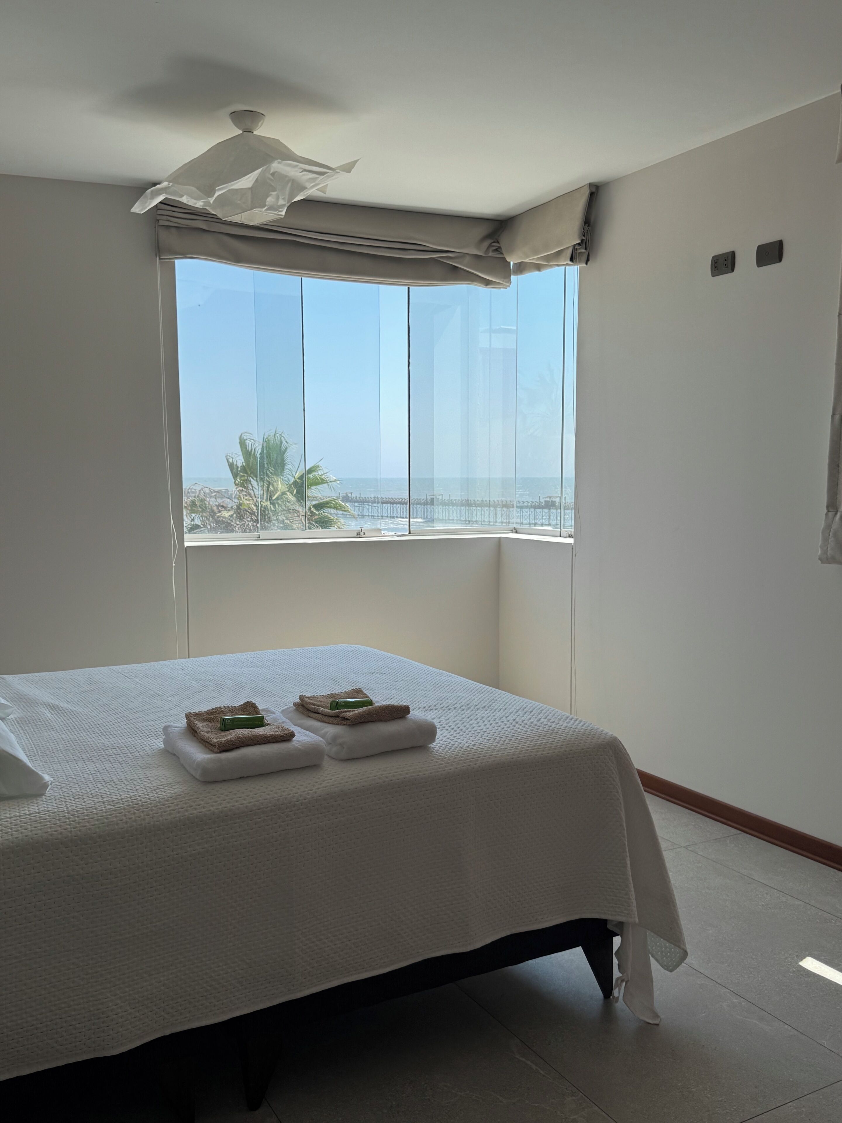 Ein Hotelzimmer mit Bett, Fenster mit Meerblick und Deckenventilator.