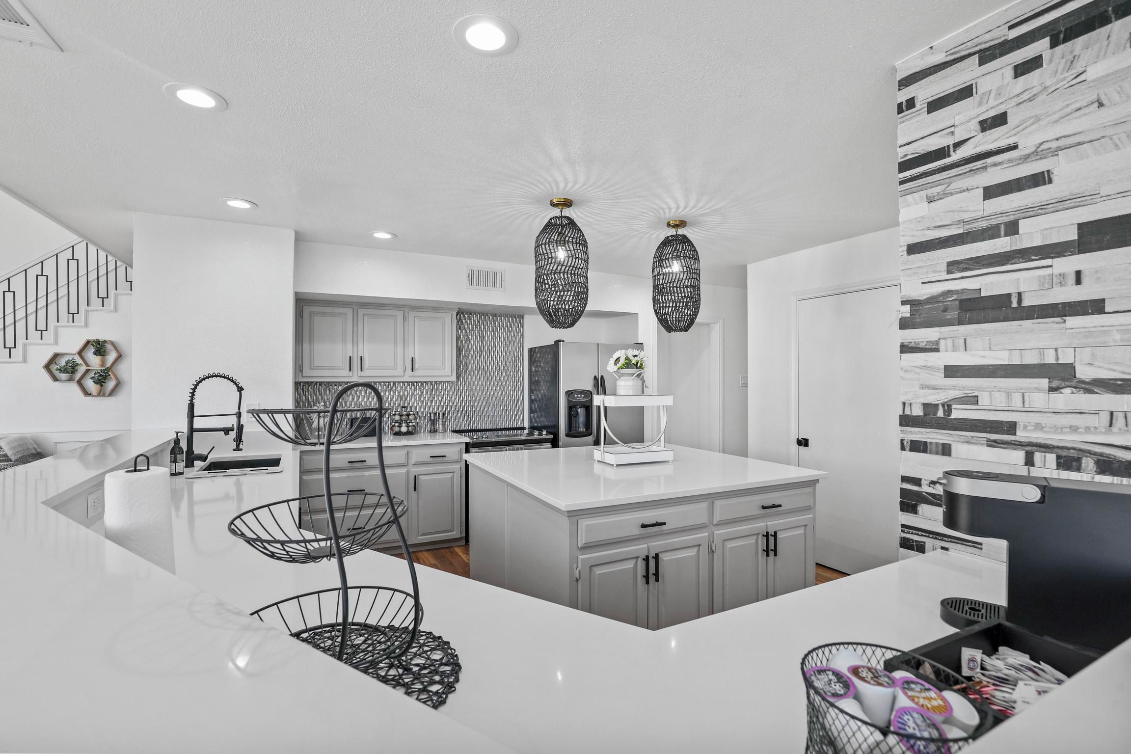 A modern kitchen with white cabinetry, a central island, and pendant lighting.