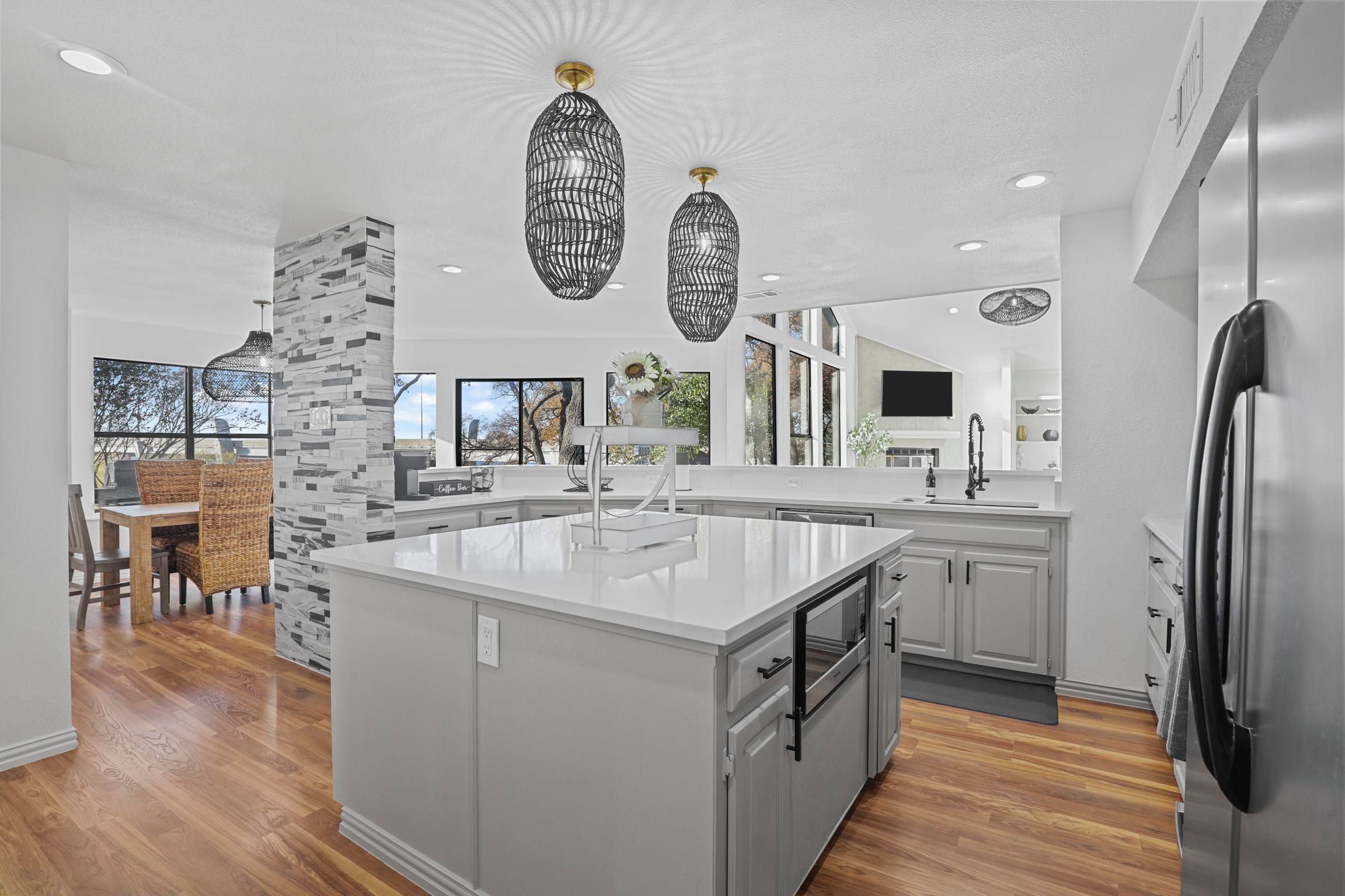 A modern kitchen with a large island, white cabinetry, and a stone accent wall.