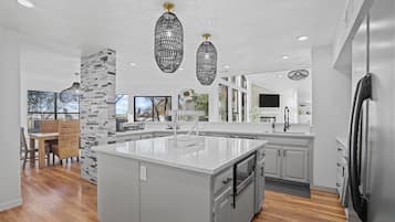A modern kitchen with a large island, white cabinetry, and a stone accent wall.