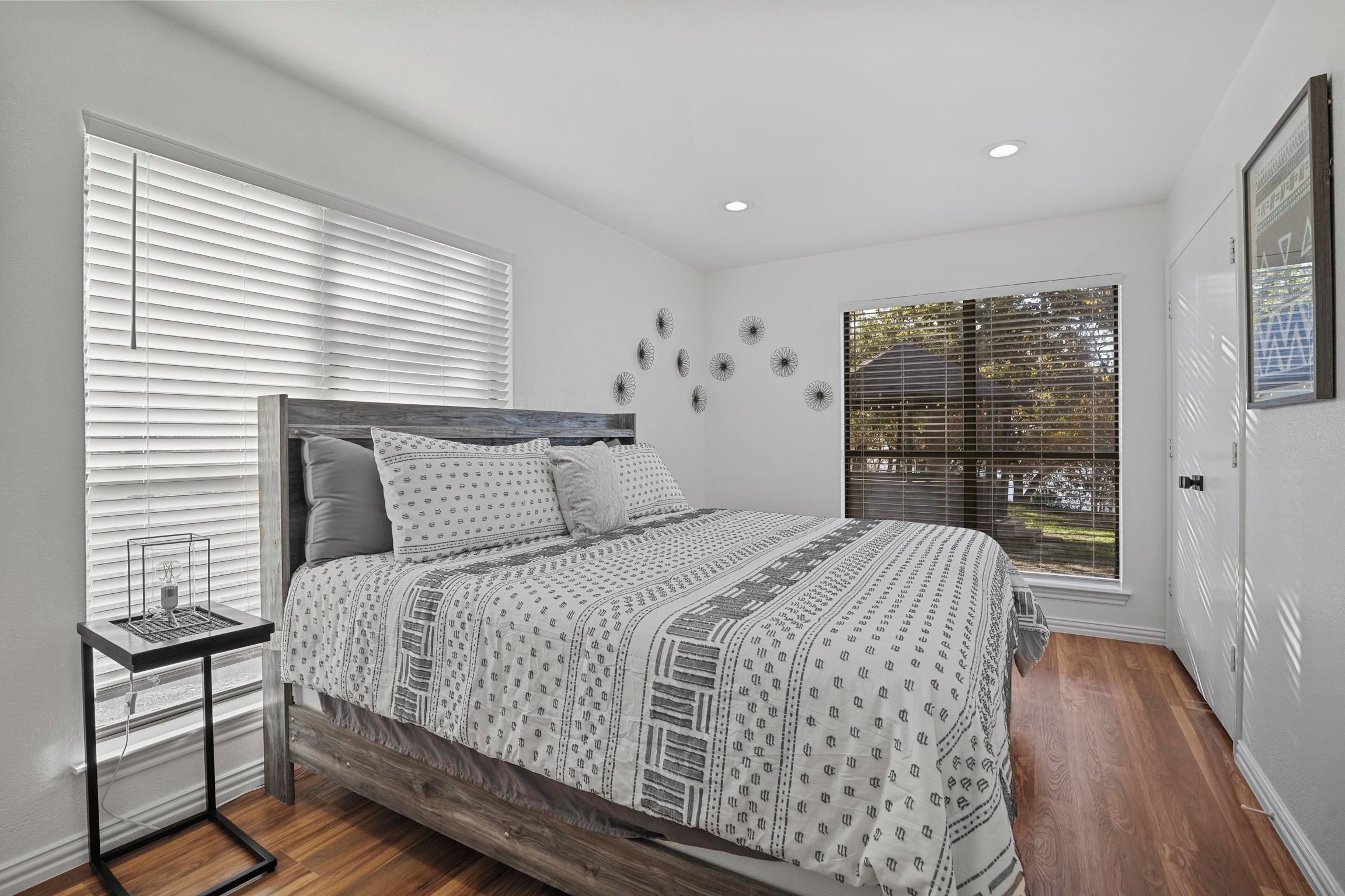 A bedroom with a bed, bedside table, and a window with blinds.
