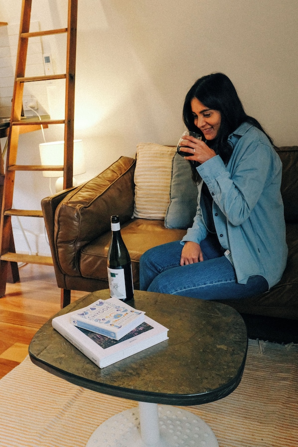 A person sitting on a couch with a bottle and a book on a small table.