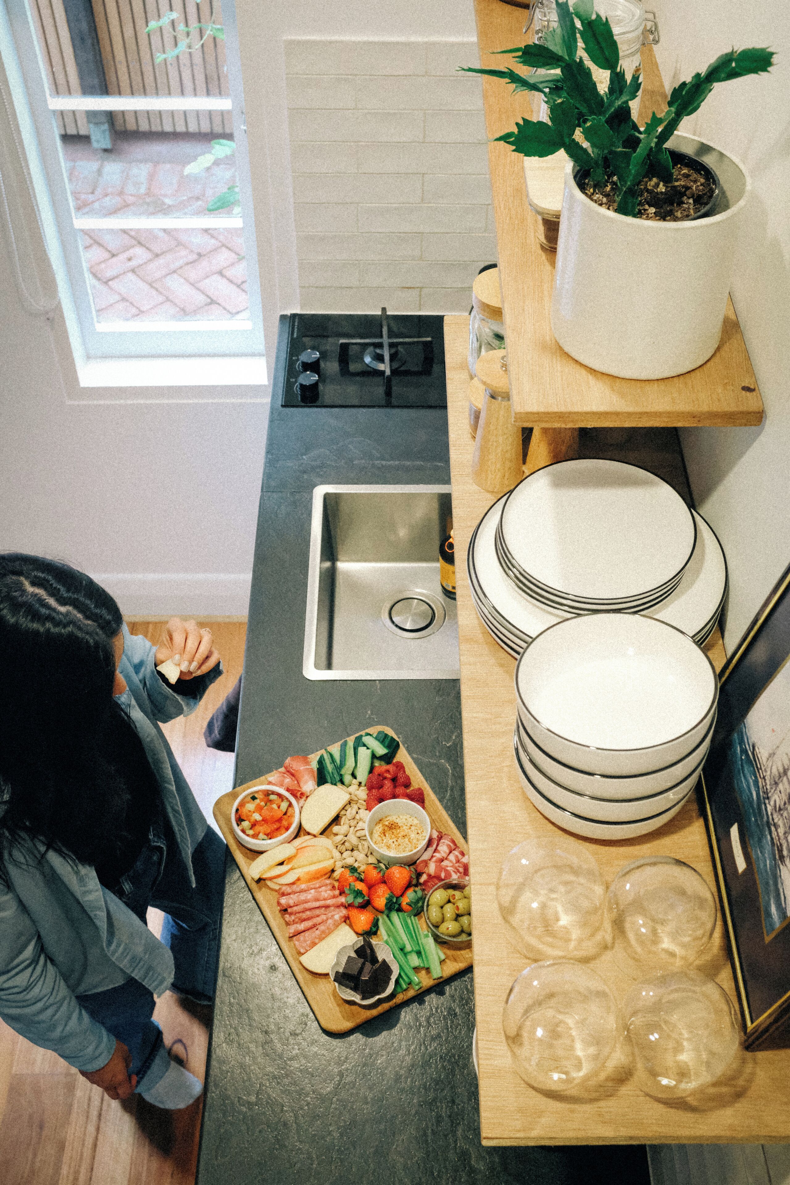 A kitchen with a countertop, sink, and a variety of food items.