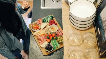 A kitchen with a countertop, sink, and a variety of food items.