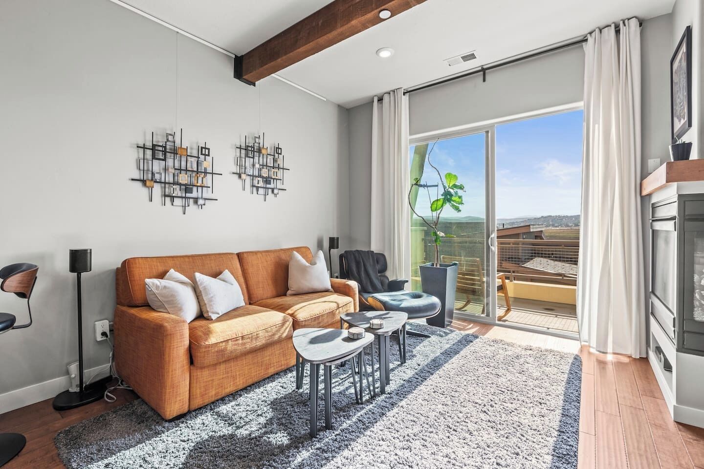 A modern living room with a sofa, coffee table, and a view of the outdoors through large windows.