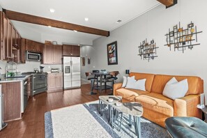 A modern kitchen with stainless steel appliances, a dining area with a wooden table and chairs, and a living room with a sofa and coffee table. - Newpark Terrace Retreat - Private Hot Tub + Nature Views • Walk to Shuttle (Park City)
