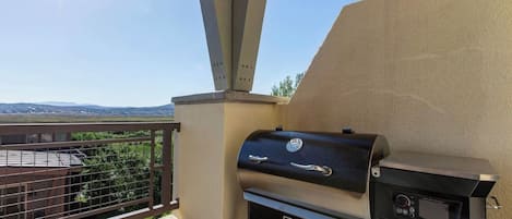 Un balcón con una parrilla, vistas al paisaje y cielo despejado.